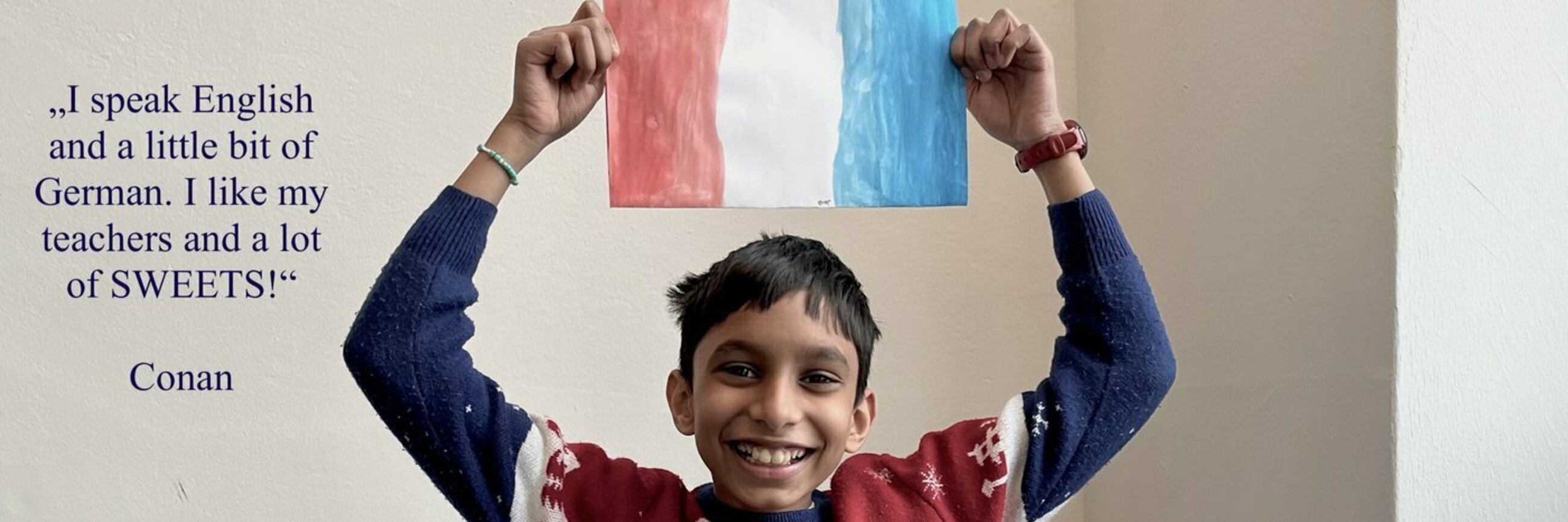 Ein Junge lacht und hält eine französische Flagge in den Händen.