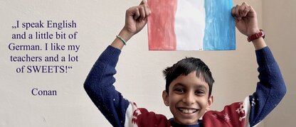 Ein Junge lacht und hält eine französische Flagge in den Händen.